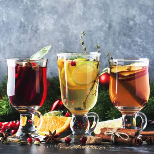 3 clear mugs of colorful mulled cocktails