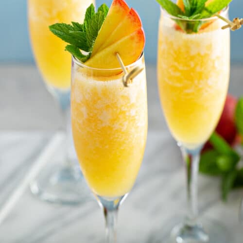 Peach Mimosa in a champagne glass with peach slices for garnish