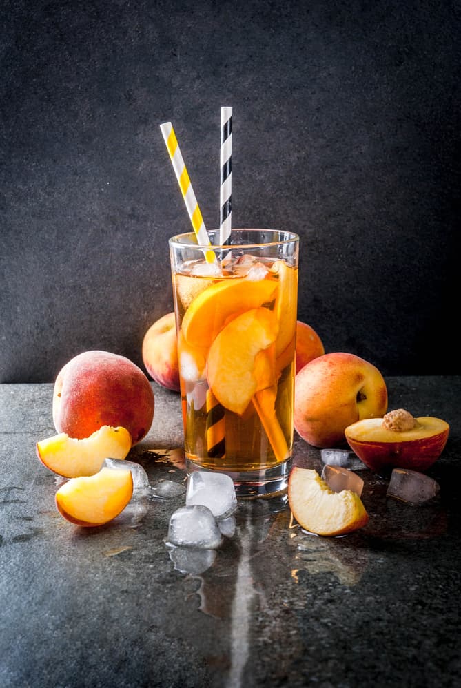The Peach Tea Party Cocktail with peaches around it
