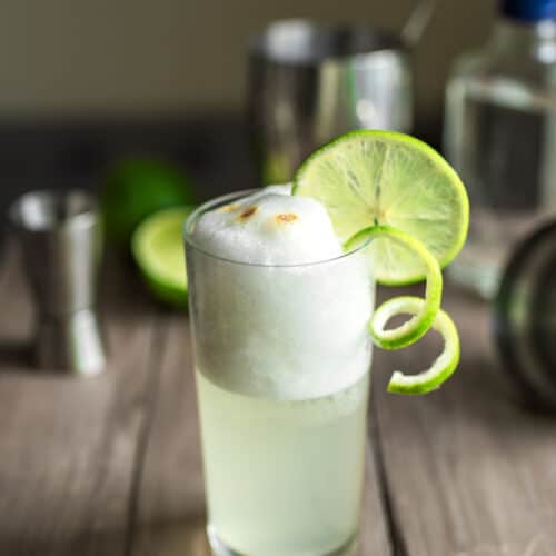 Pisco Sour Cocktail in a tall glass with a foamy top and a lime garnish