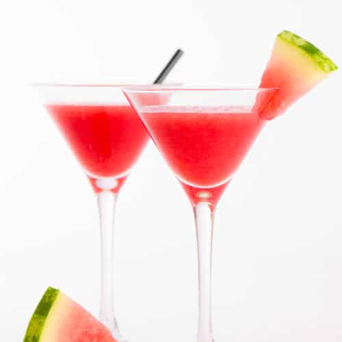 2 Watermelon Martinis in martini glasses with a watermelon wedge next to it