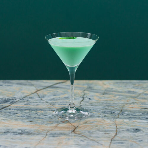 Mint green grasshopper Cocktail in a Martini glass on a table