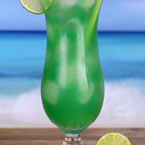 My Green Eyes Cocktail In a Hurricane Glass on a beach