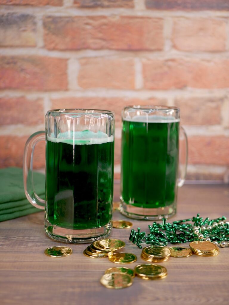 Two mugs of green beer with St. Patrick's Day trinkets