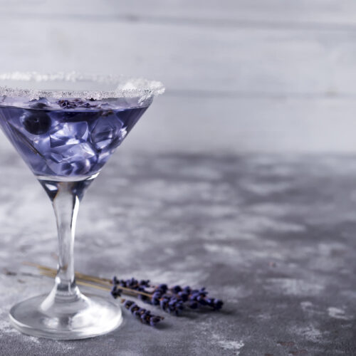 Martini glass with a purple mixture of a Lavender Martini and sprigs of lavender for garnish.