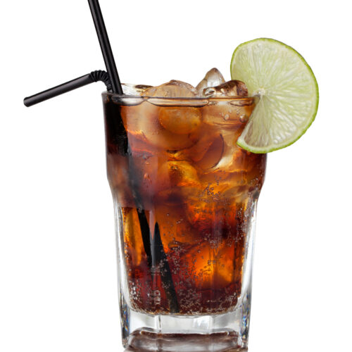 Cuba Libre cocktail with ice and a lime