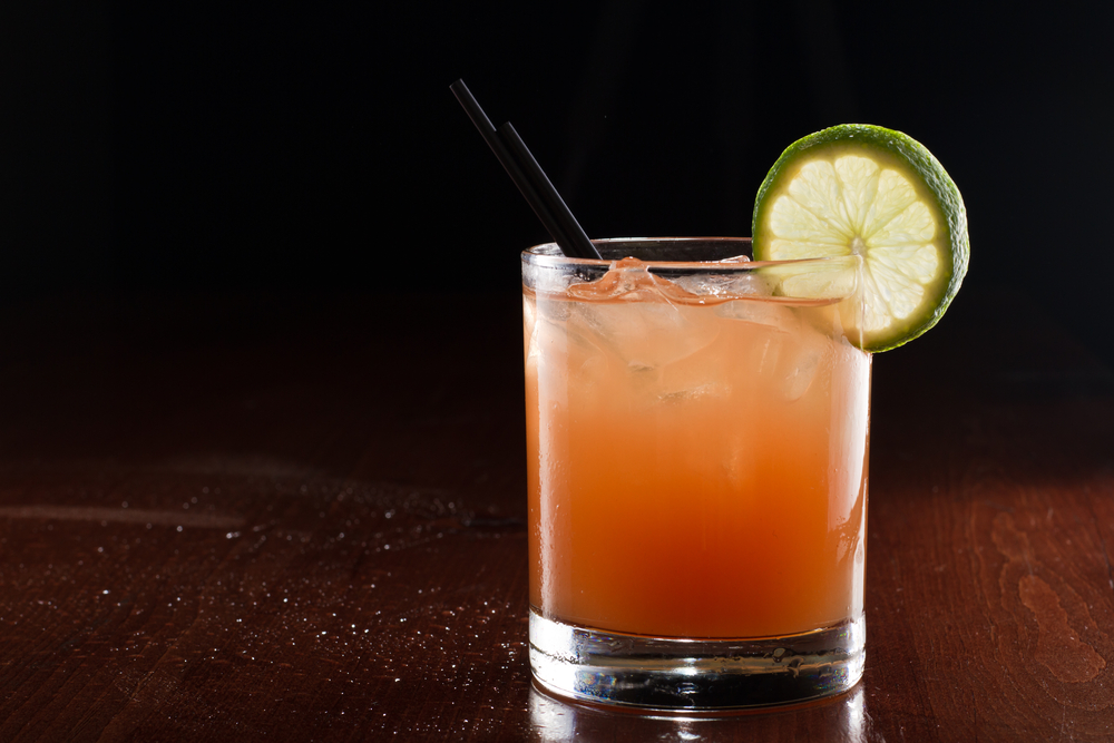 Easter Cocktail Recipes include screwdriver cocktail served on a dark bar setting garnished with a lime wheel