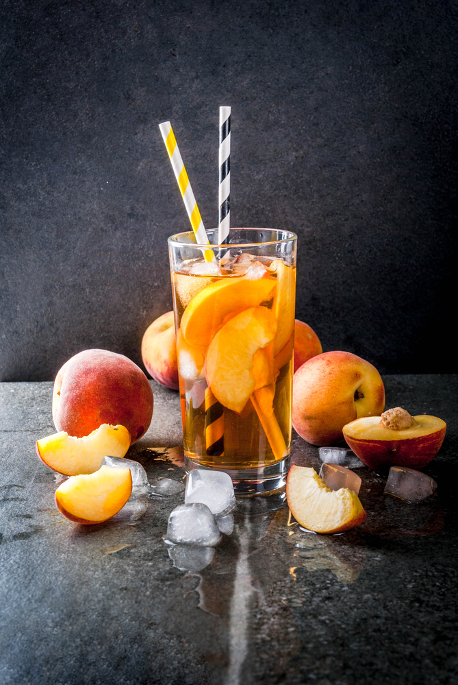 Low Sugar cocktail made with unsweetened tea and peaches in a glass with straws