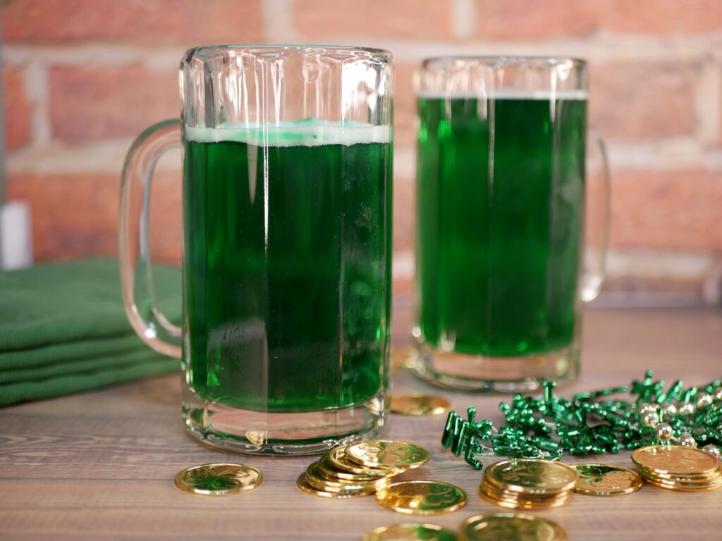 St. Patrick's Day Cocktails. Two mugs filled with green beer next to gold coins
