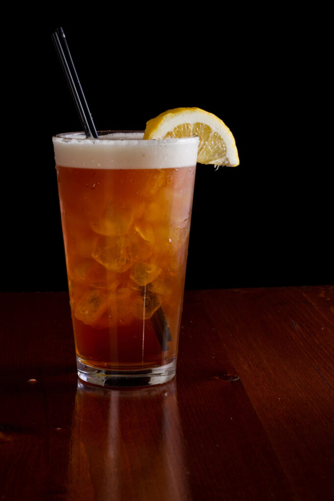 Frothy Long Island Iced Tea with a Lemon wedge and a straw