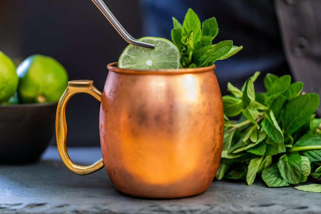 A brass-colored mug with sliced lime and mint