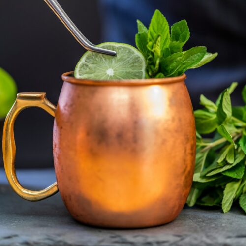 brass-colored mug with sliced lime and mint with an Irish Mule inside