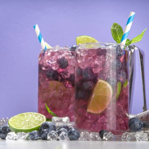 Two glasses of Blueberry Vodka Lemonade Fizz with ice and straws.