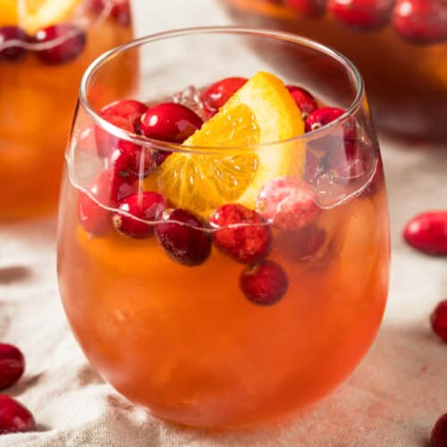 Festive Holiday Punch in a glass with a slice of orange and cranberries on top