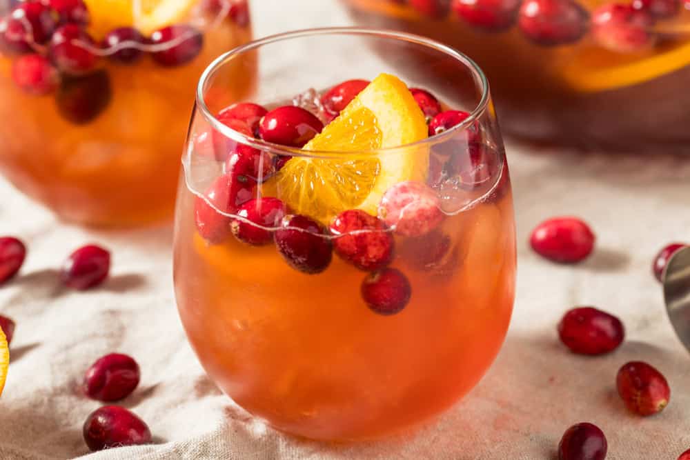 Festive Holiday Punch in a glass with a slice of orange and cranberries on top