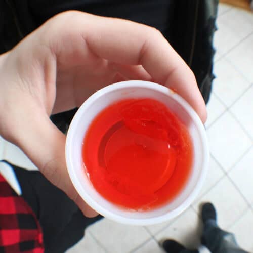 Jello shot cup with reddish orange jello inside