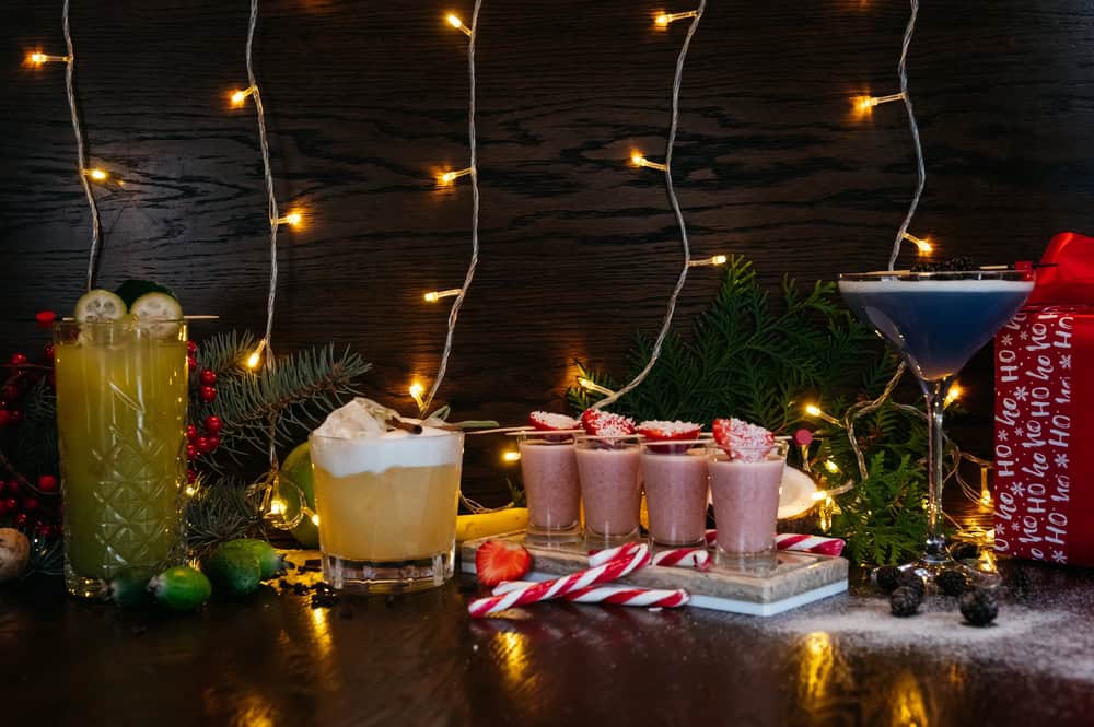 4 different cocktails with white twinkle lights in the background and Christmas decorations