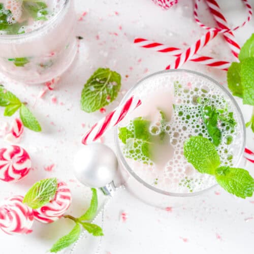 Winter White Mojito cocktail in a glass with candy canes on table