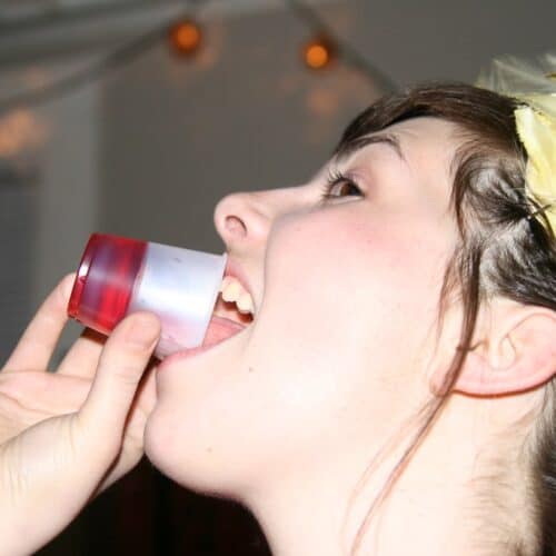 A female drinking a red jello shot