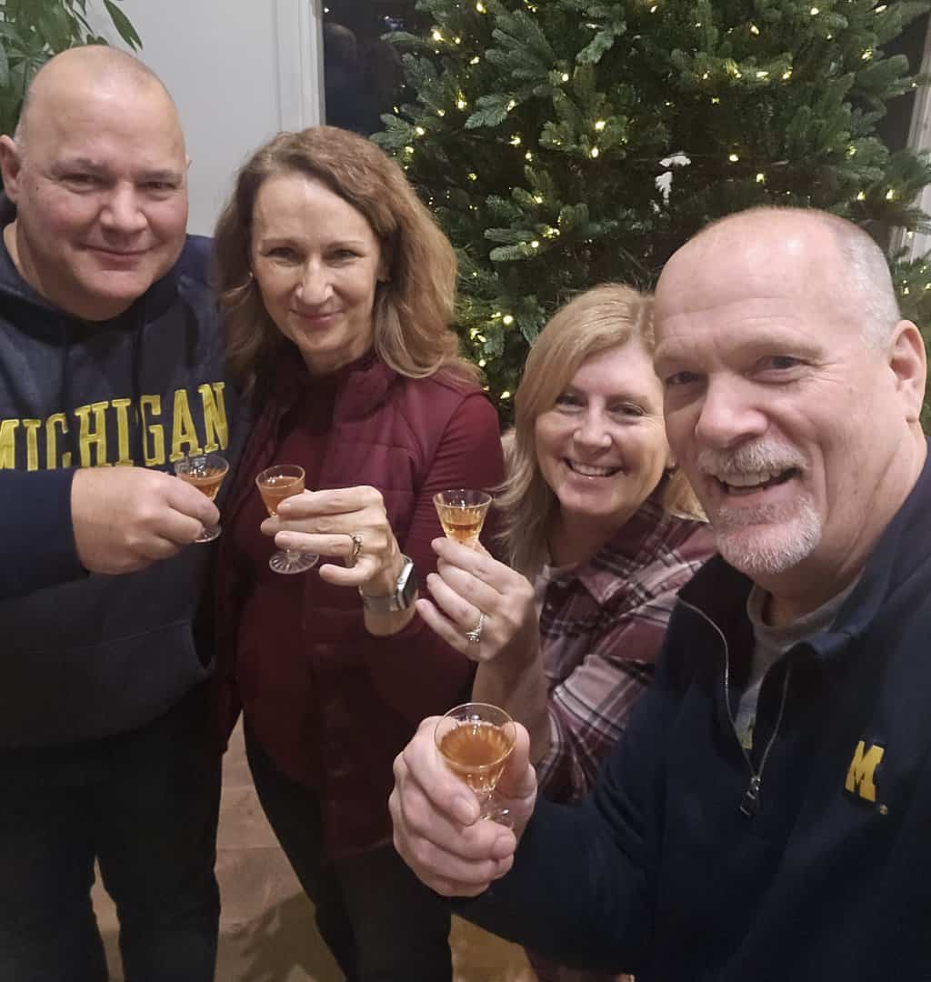 Four people around a tree toasting the Holidays