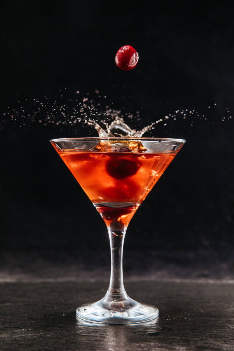 Arrowhead Red Cocktail with cherries splashing into martini glass