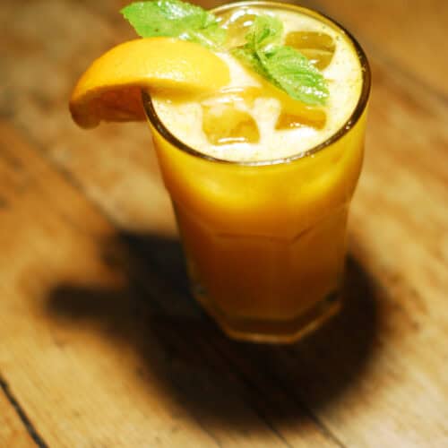 Bourbon Orange Fizz Cocktail in a glass with ice, slice of orange and mint