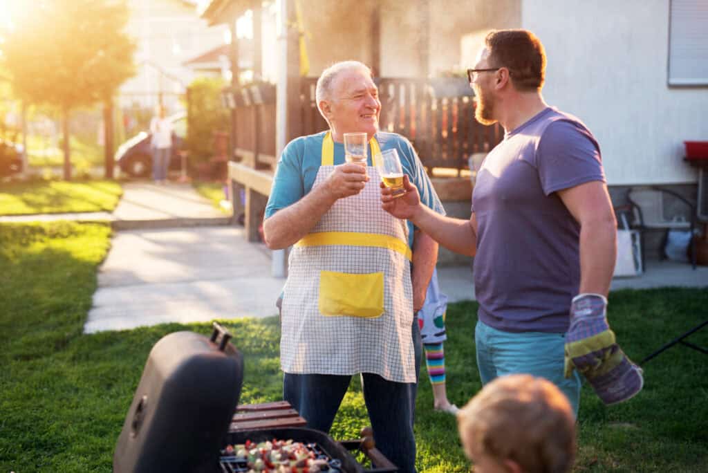 Father and son are drinking beer and grilling together.