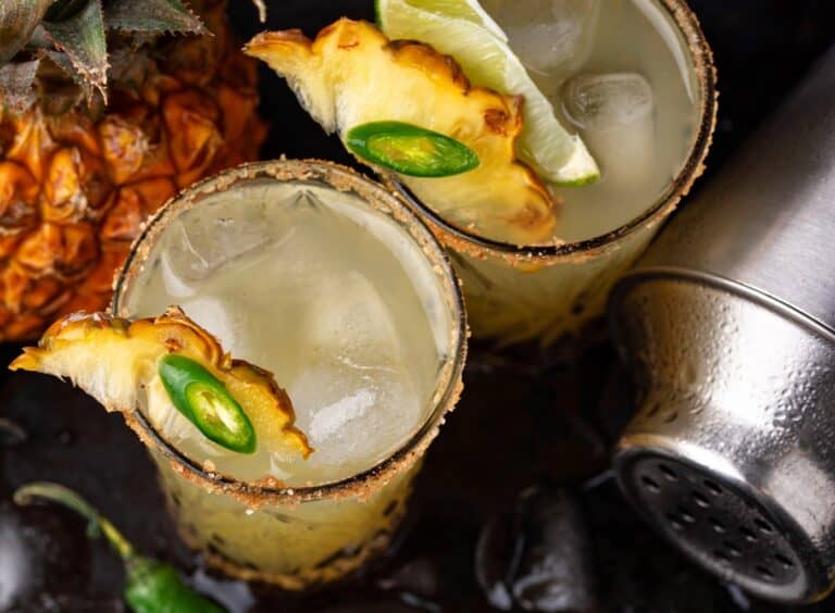 2 Swicy Cocktails including Pineapple Jalapeno Smash in glasses on a tray with ice