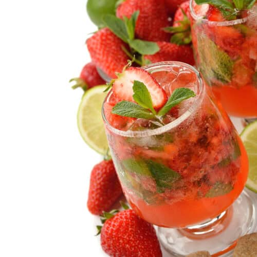 Strawberry Serrano Mojito in a glass with strawberries around it