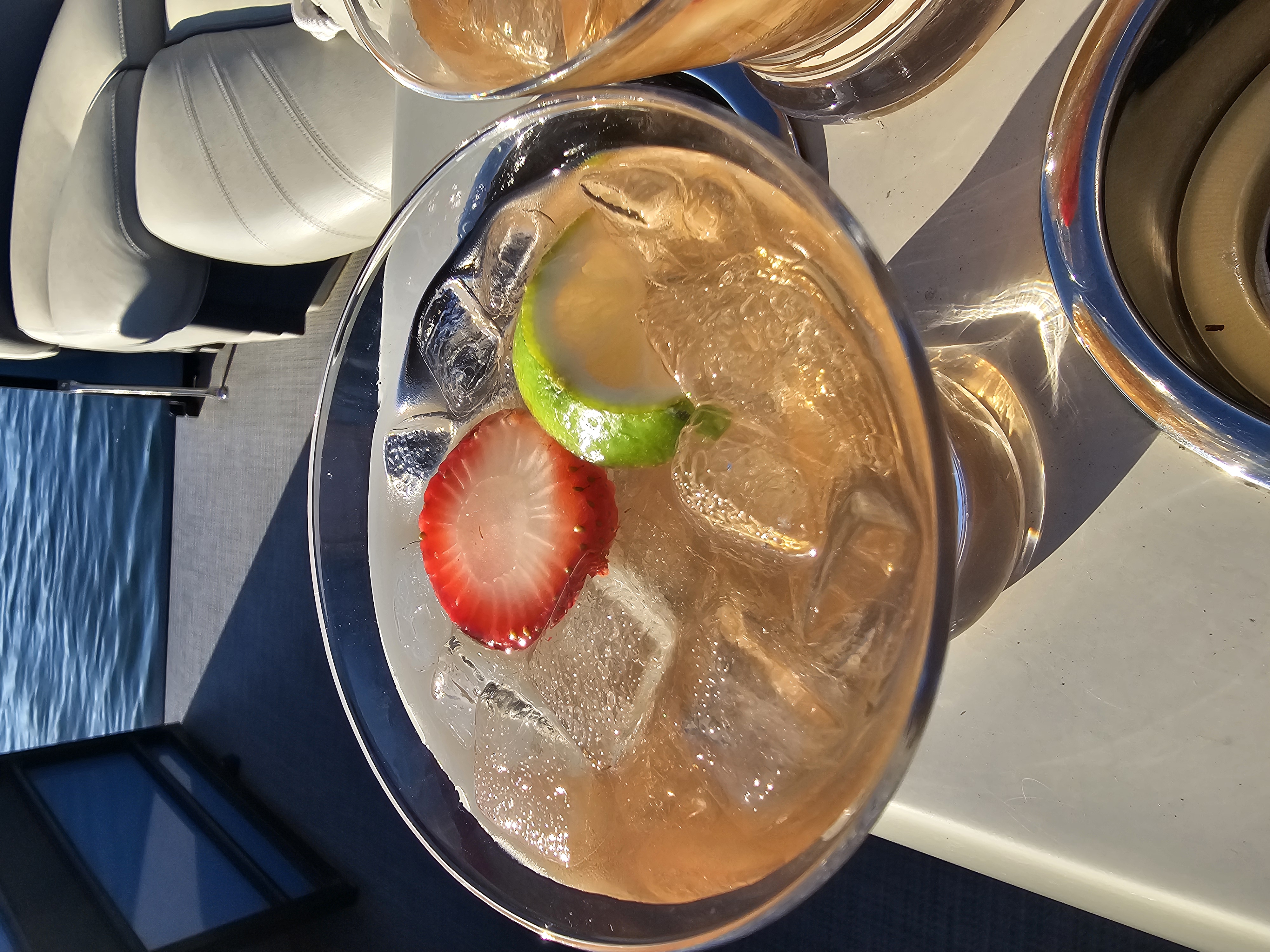 Cherry Court Cooler Cocktail with a strawberry and lime garnish on a boat