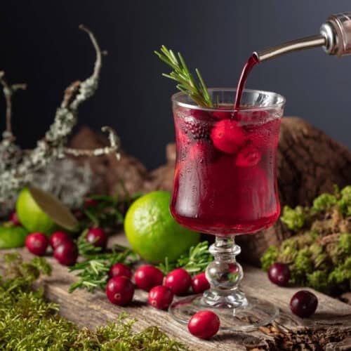 Cranberry Margarita in a glass with lime and cranberries on a wooden table