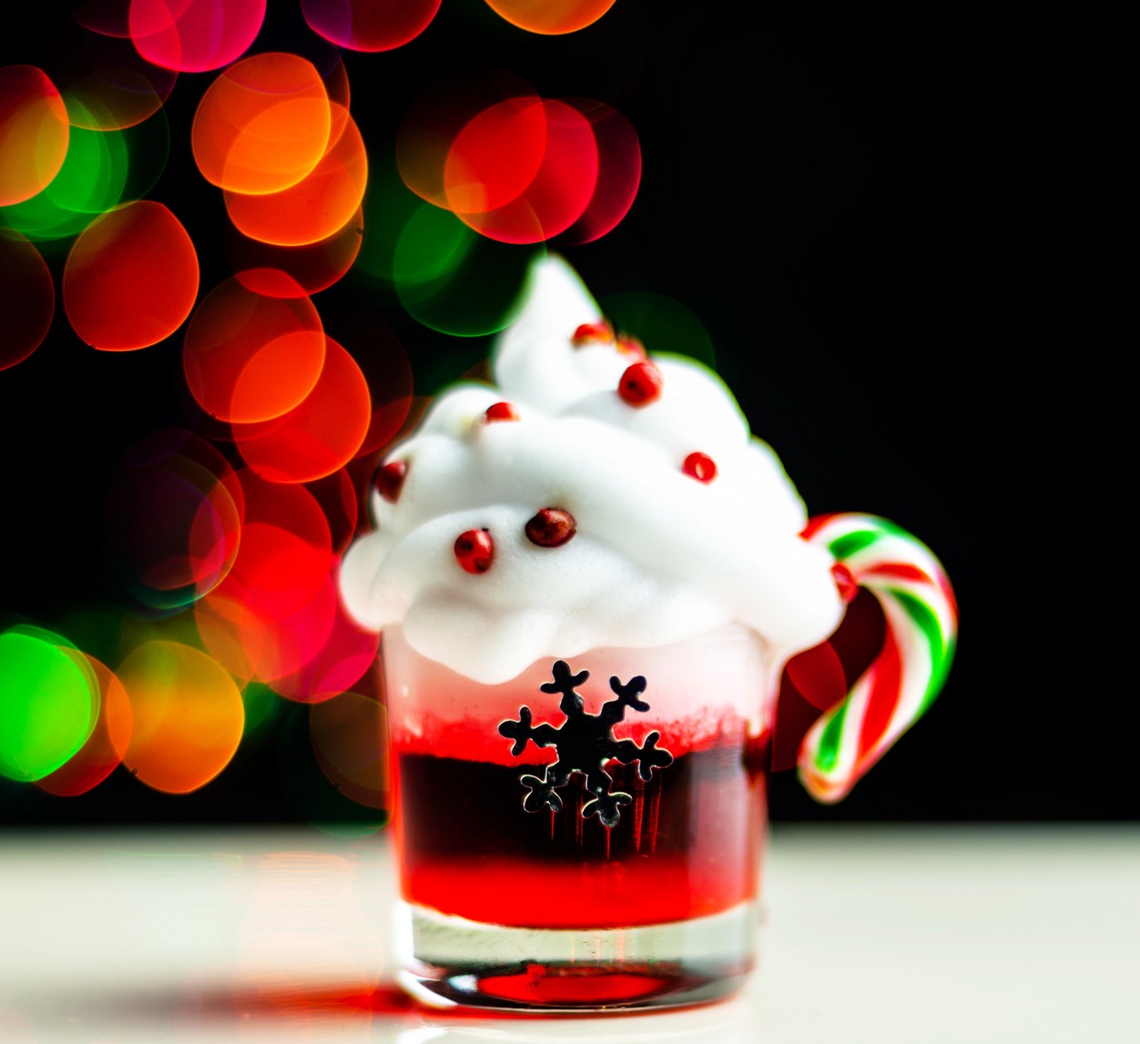 Festive Holiday Shots include this red one with a whipped cream topper and a candy cane sticking out.