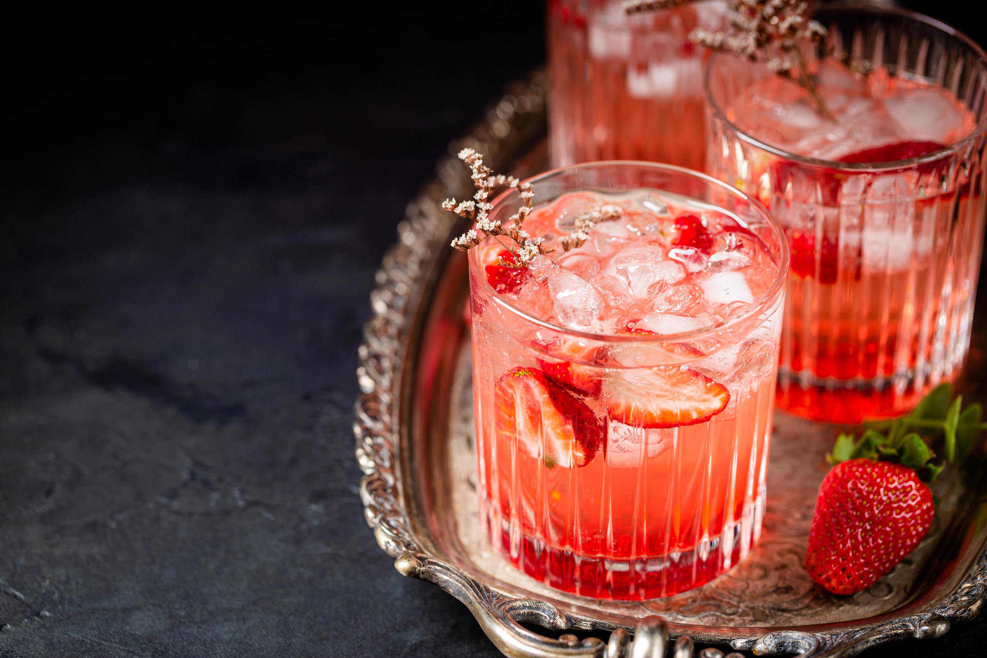 Pink Whitney Strawberry Kiss cocktail on a silver tray.