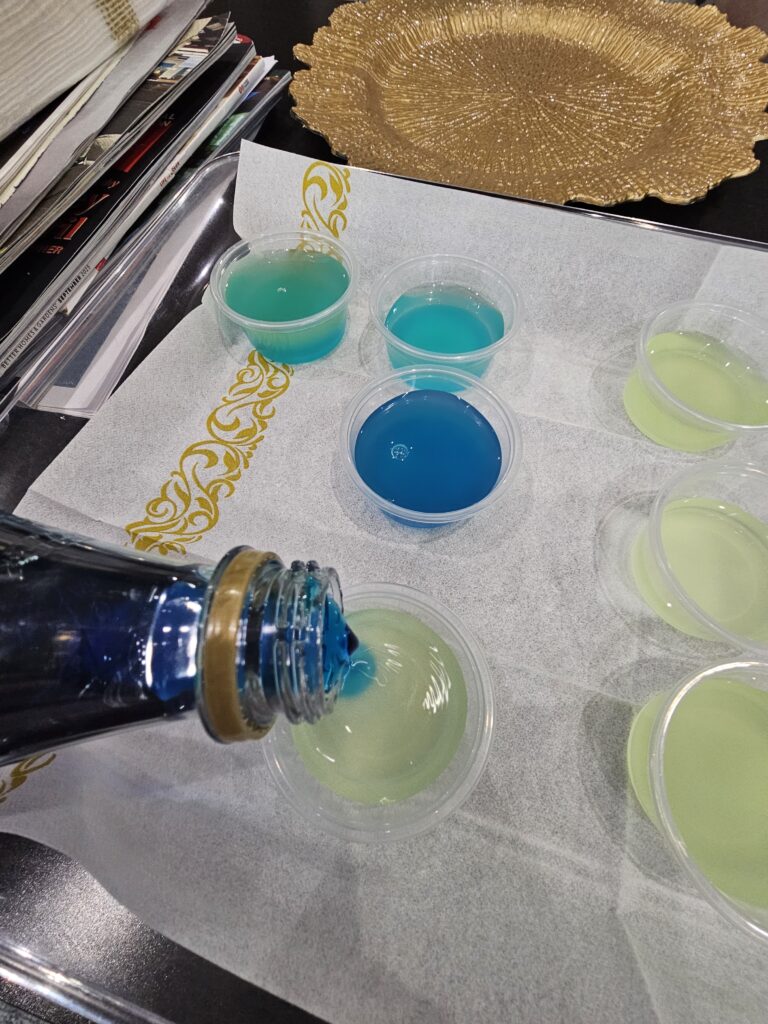 Pouring blue liquid into shot cups for Happy Hour