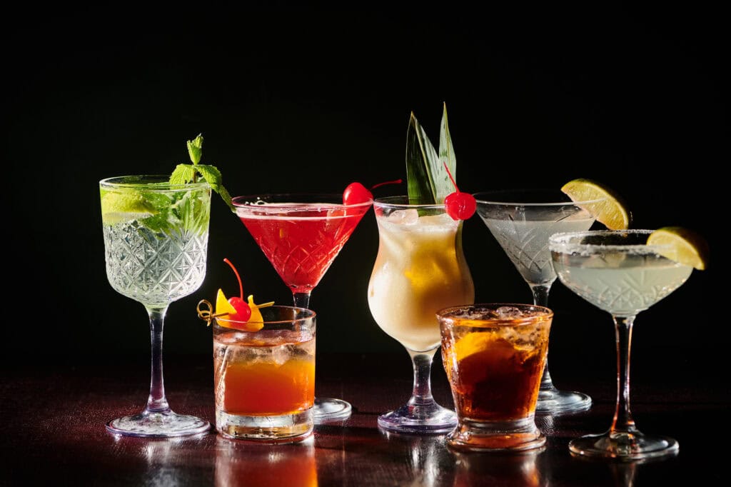 7 different cocktails with a variety of garnishes.