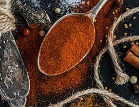 Tajin spice on a spoon over a dark background,