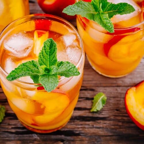 Glass filled with peach whiskey lemonade with ice and garnish