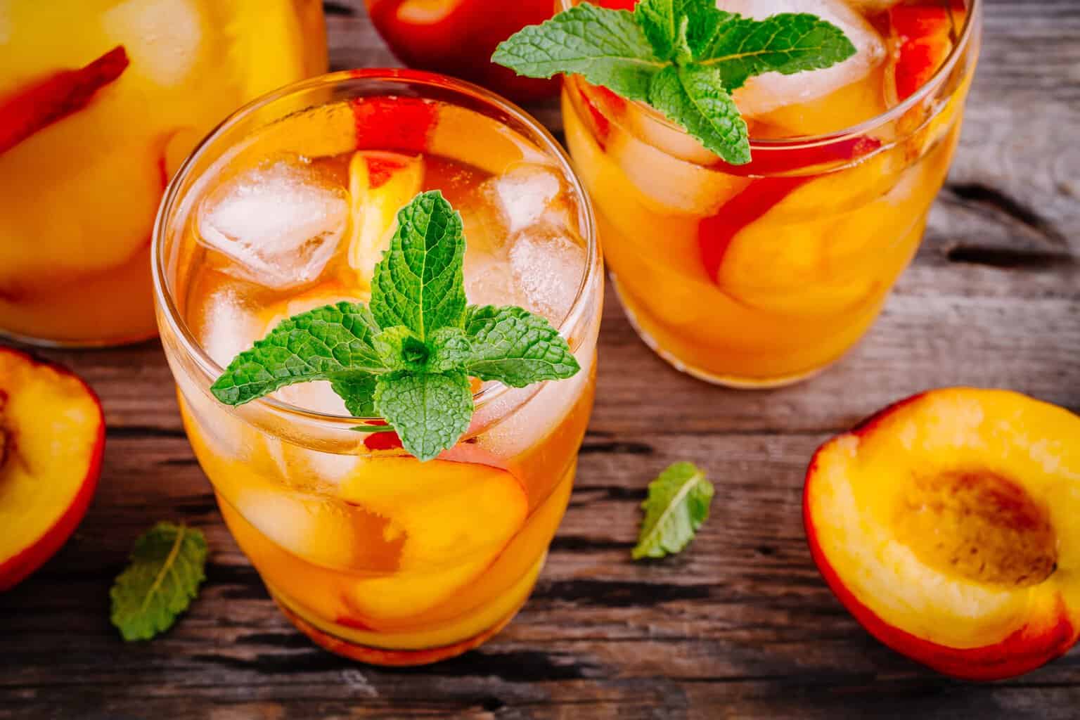 Glass filled with peach whiskey lemonade with ice and garnish